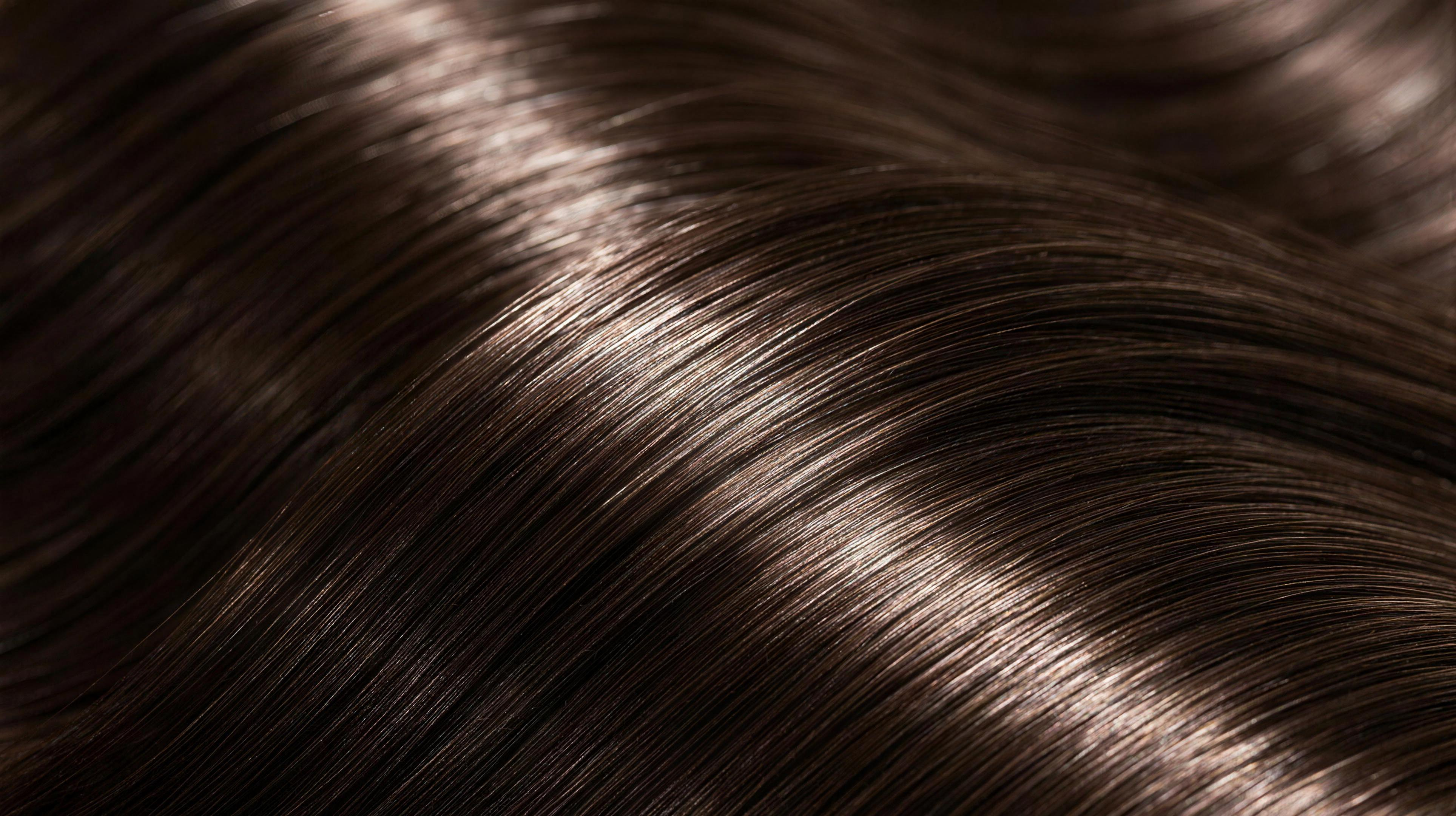 Close-up of glossy, smooth, frizz-free brunette hair catching studio light
