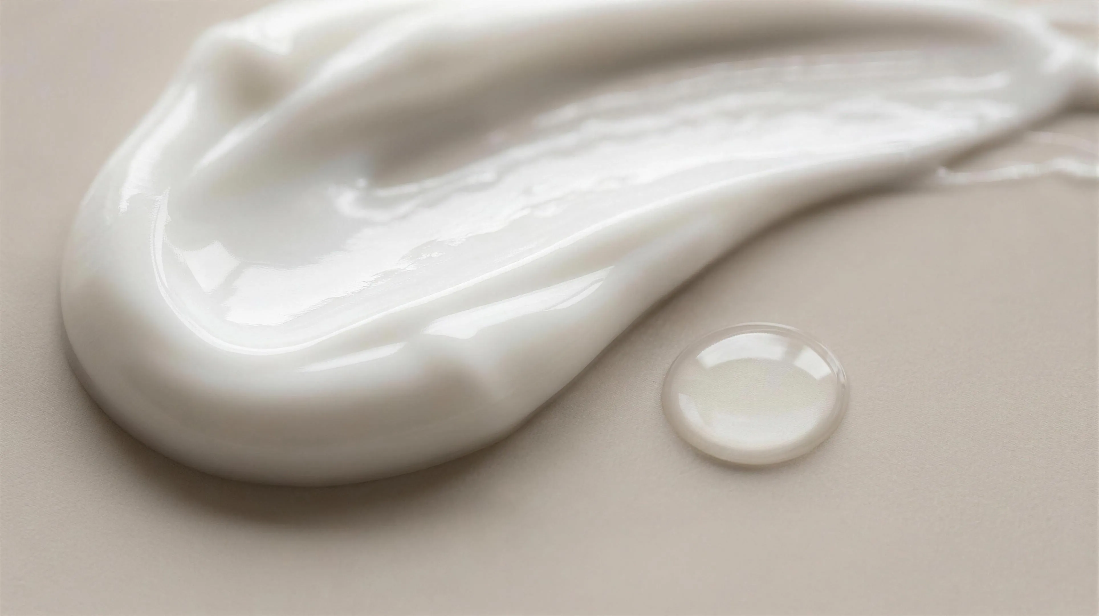 Macro texture of glossy white cosmetic cream and a clear silky serum drop